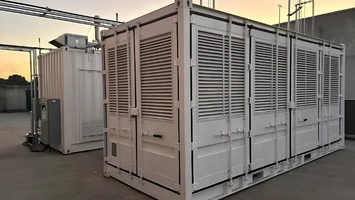 Modular containerised long-duration energy storage units with louvred panels on a flat rooftop at dusk